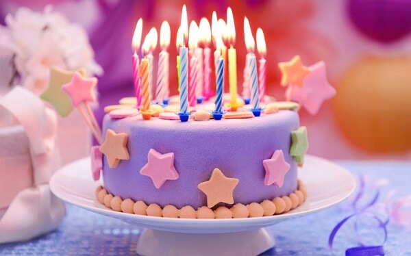 violet colored birthday cake designed with stars with candles on top
